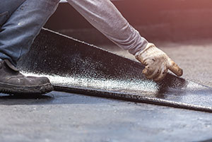 Worker installing tar foil on the rooftop of building.